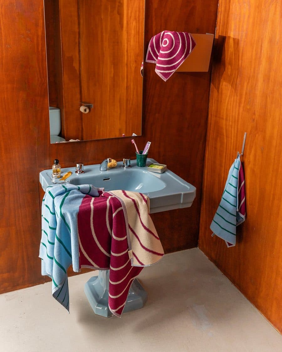 Tarta Gelatina towels hanging in a wood-panelled bathroom